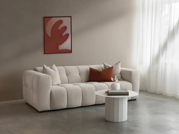canapé devant baie vitrée, rideaux blancs tableau orange, table basse blanche et ronde